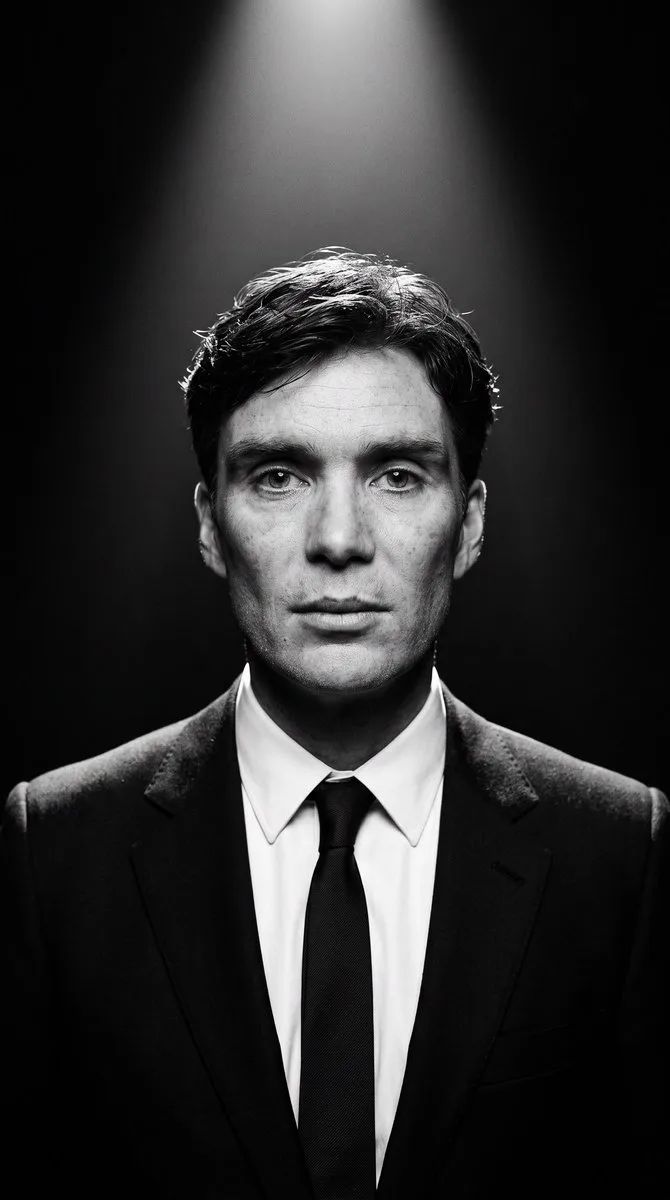 A high-contrast black and white studio portrait of a person in a formal suit.