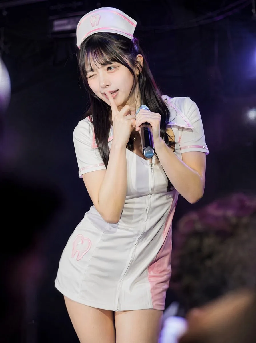 Japanese idol in a cute dental nurse costume performing on stage with a microphone (4)