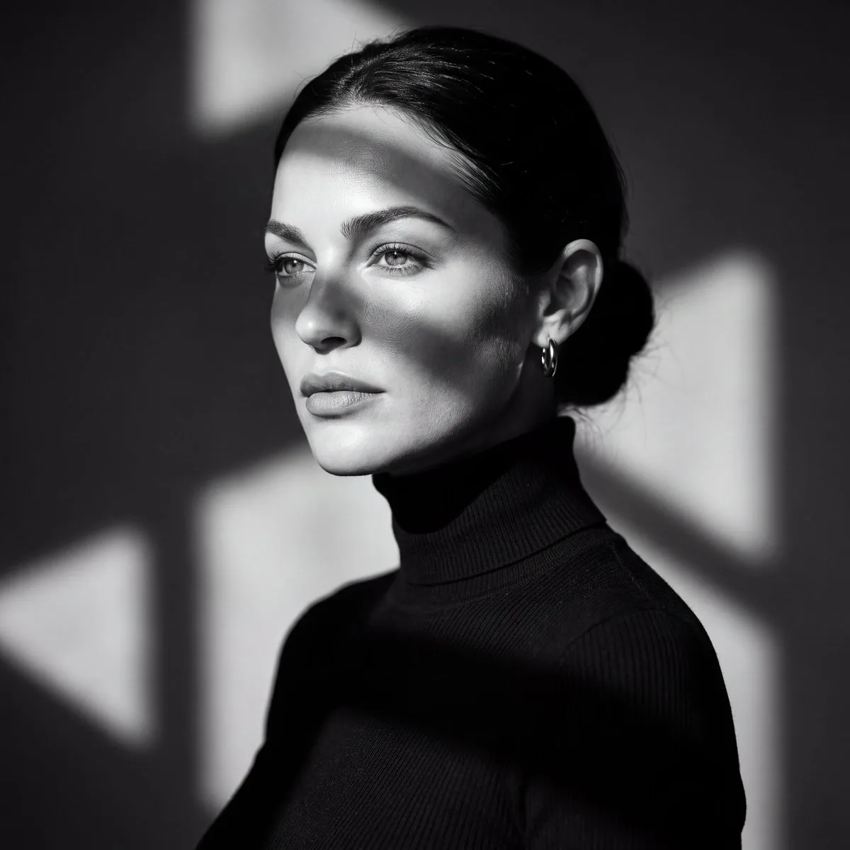 A woman in a black turtleneck posing in a studio with dramatic lighting.