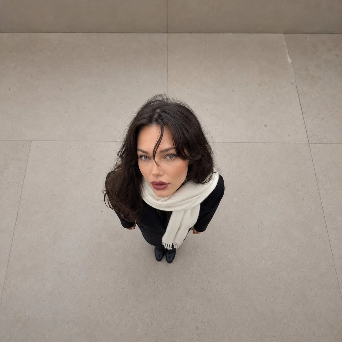 Overhead photo of a person with an exaggerated large head and tiny body on stone flooring.