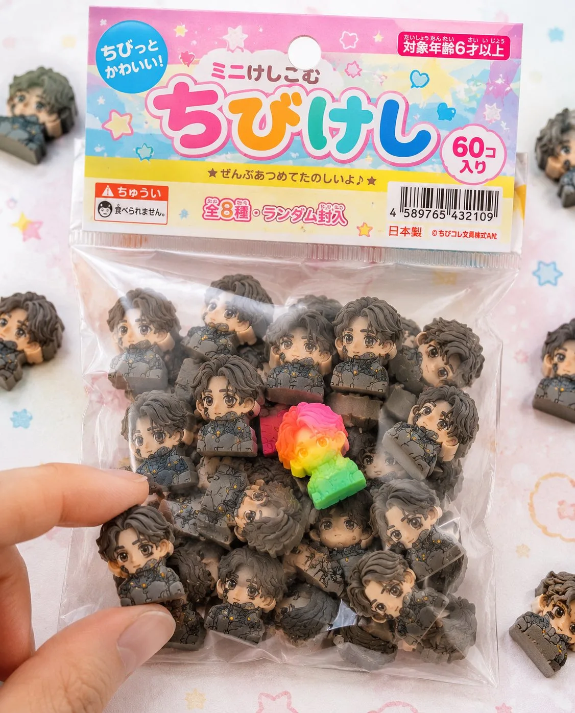 Packaged Japanese mini eraser blind bag toy with scattered tiny colorful erasers on a table.
