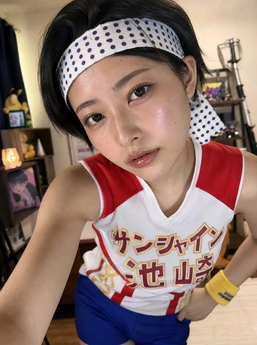 A Japanese female cosplayer with short black hair in her apartment.