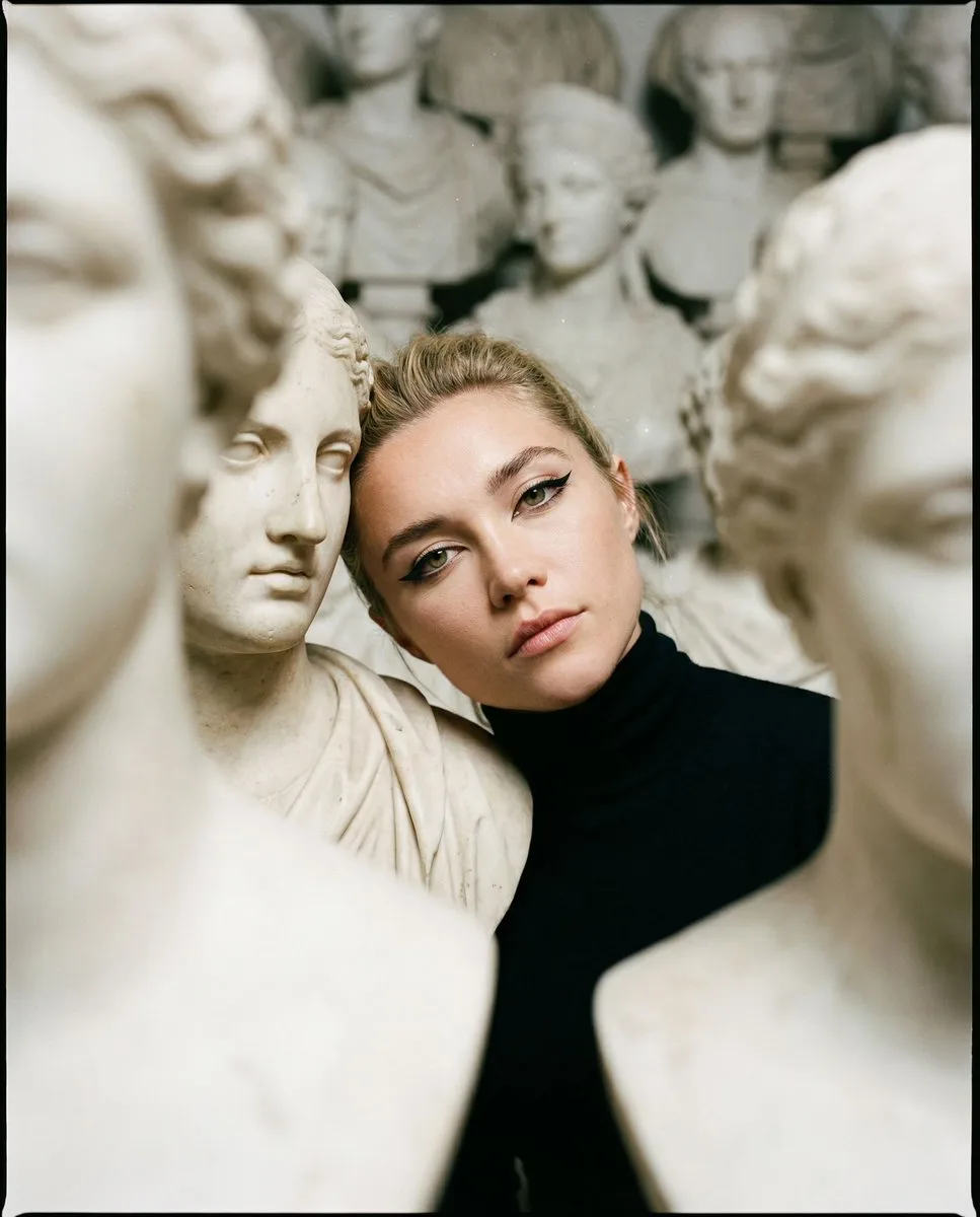 Woman in black turtleneck among dense white marble busts.