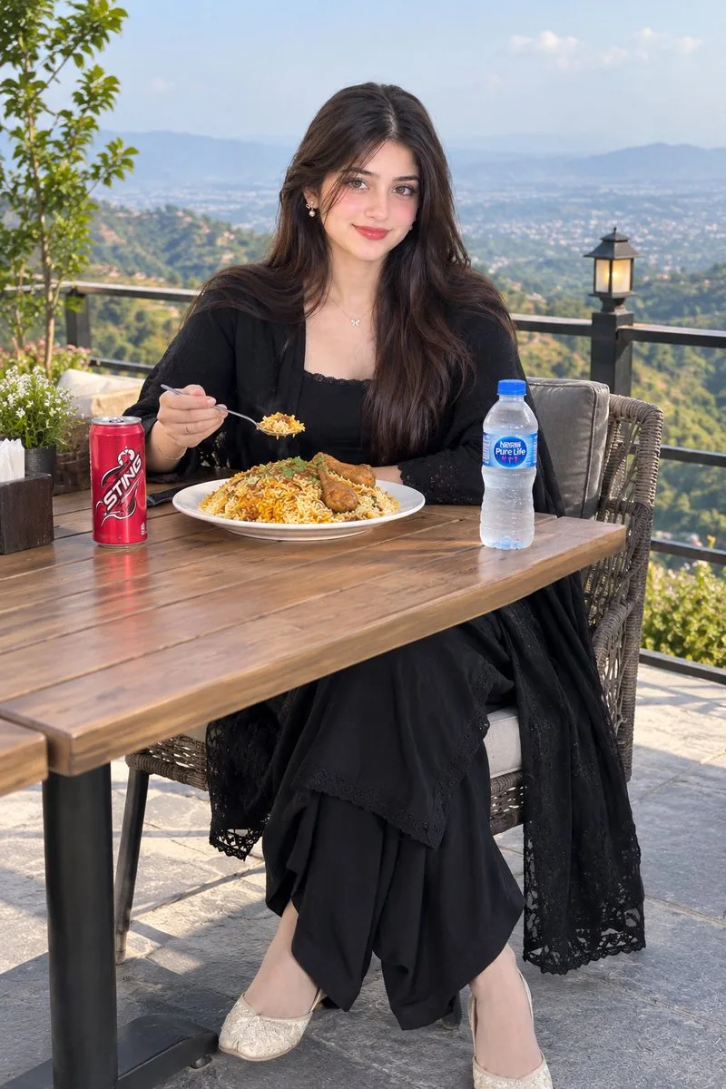 A woman eating biryani at a scenic outdoor hilltop table.