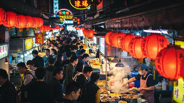 Crowded night market in Taipei with glowing lanterns and food stalls