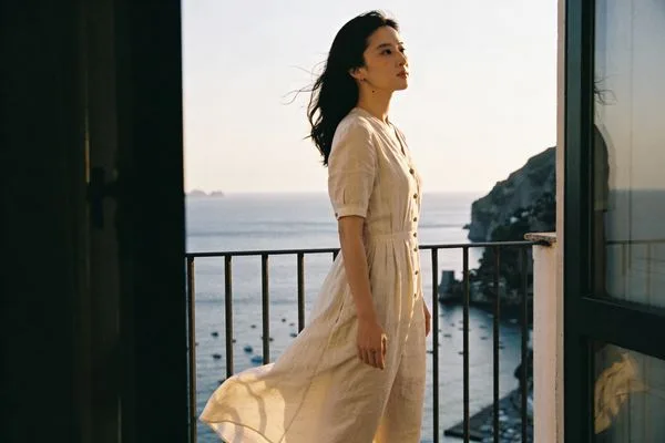 Elegant woman in a linen dress on an Amalfi terrace at sunset.