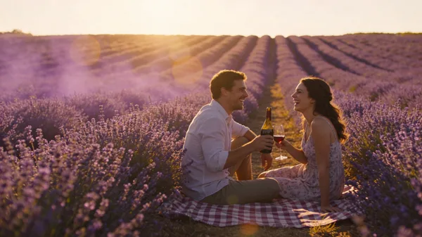 A couple enjoying a romantic sunset picnic in a purple lavender field in Provence.